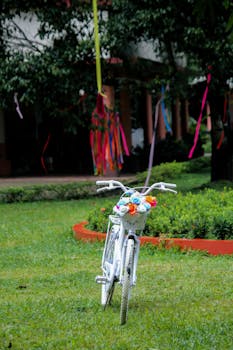 A beautifully decorated white bicycle with flowers in the basket in a vibrant outdoor garden.