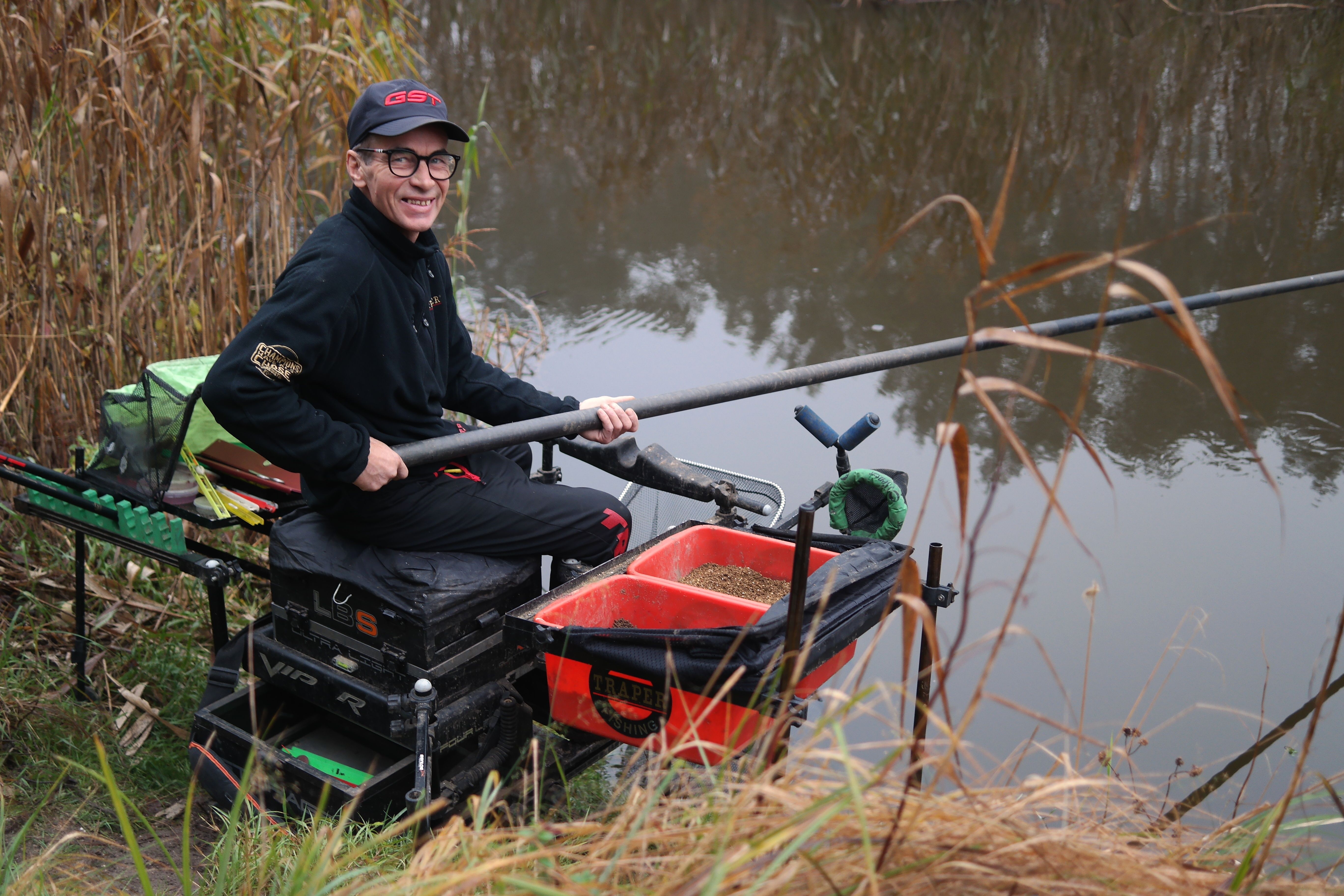 Man Fishing at Riverside with Fishing Gear · Free Stock Photo