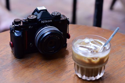 Free A classic camera and iced latte on a wooden table, evoking creativity and relaxation. Stock Photo