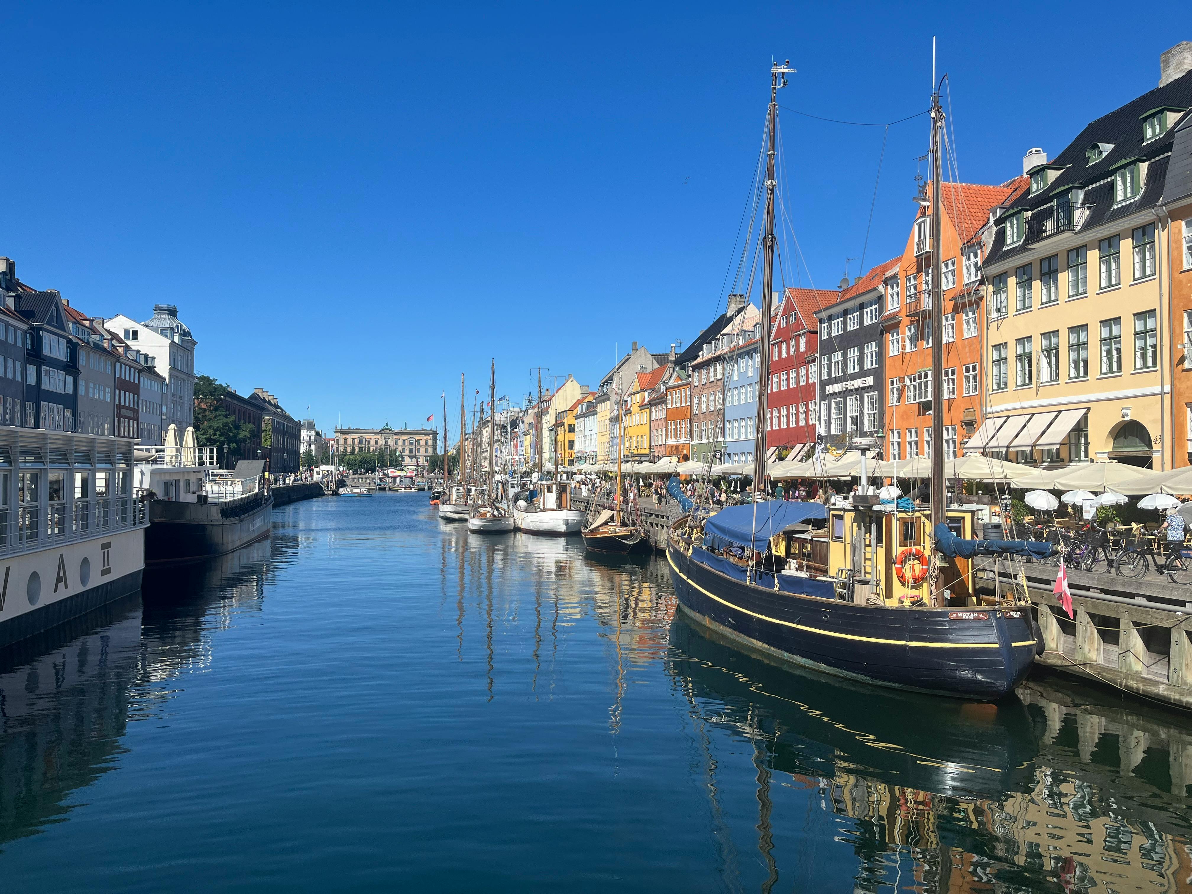 Bright day at Copenhagen's Nyhavn with colorful buildings and classic ships.