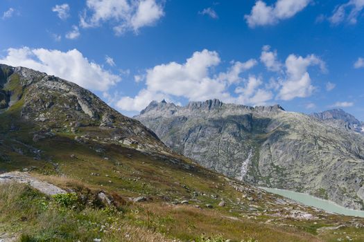 Breathtaking view of the Swiss Alps under a clear blue sky, showcasing rugged mountains and a serene valley.