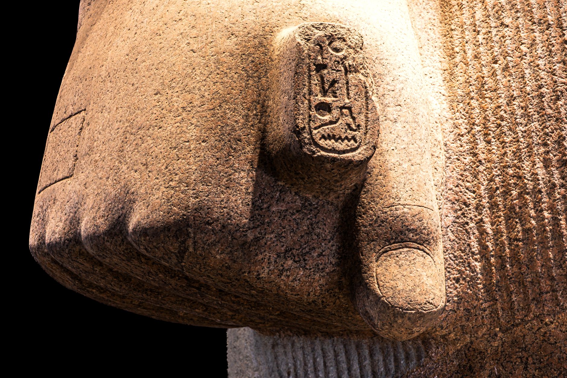 Detailed view of an ancient Egyptian statue's hand with hieroglyphics, showcasing historic artistry.