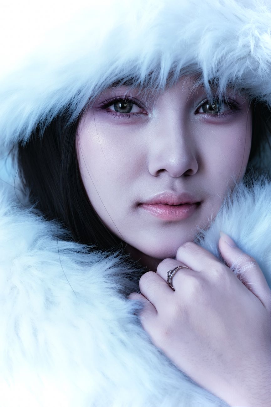 Close-up portrait of a woman wearing a white fur coat, evoking a sense of winter elegance.