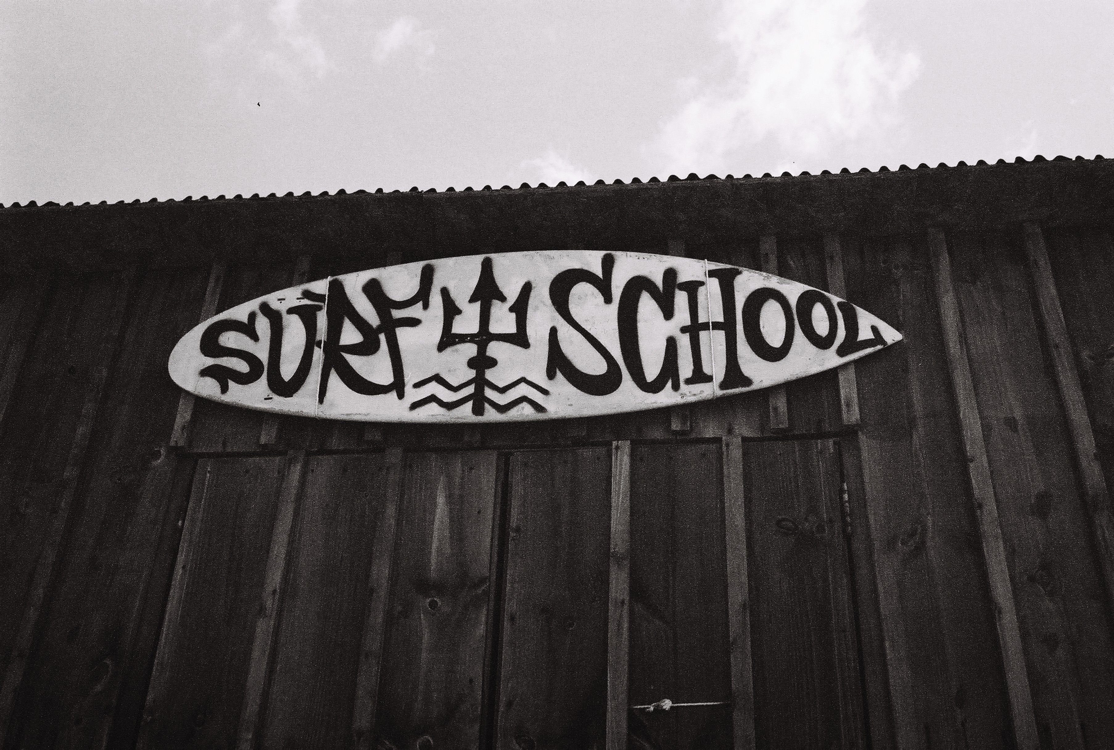 Monochrome Surf School Sign on Wooden Wall · Free Stock Photo