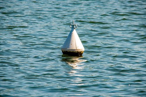 Free A metal buoy floats amid gentle waves under sunlight in Ingolstadt, Bavaria. Stock Photo