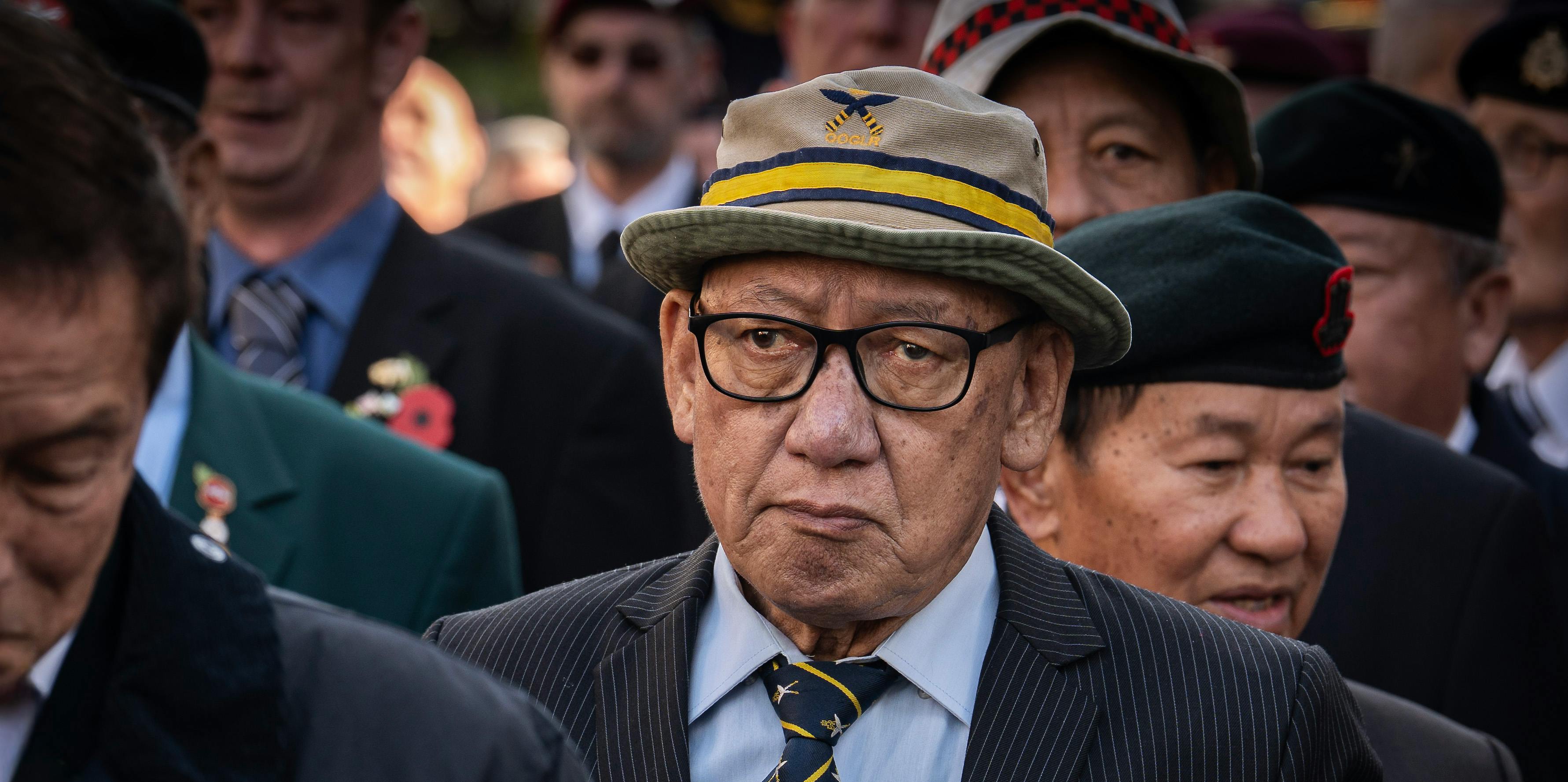 A gathering of veterans wearing hats and suits, honoring their service.