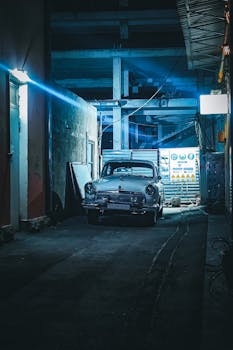 A classic vintage car parked in a dimly lit urban alleyway in Yerevan at night, with a cool tone and atmospheric mood.