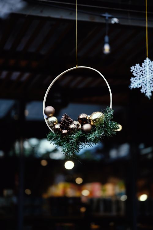Free Hanging holiday wreath adorned with pinecones and baubles in a cozy setting. Stock Photo