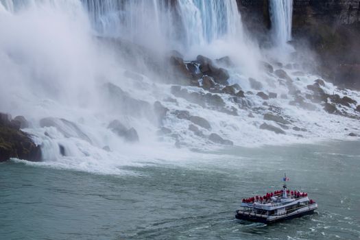 Tour boat approaches the misty Niagara Falls, capturing its grandeur and power.