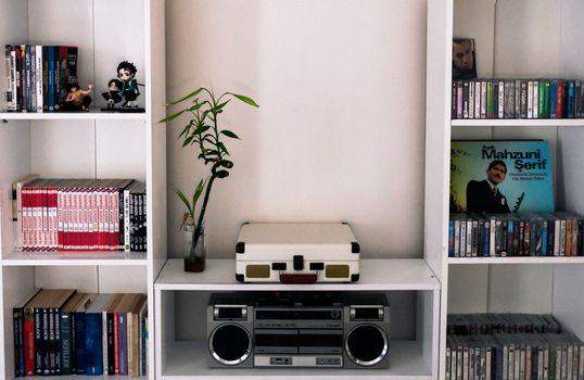 A neatly organized bookshelf with vintage audio equipment, books, and decorative items.