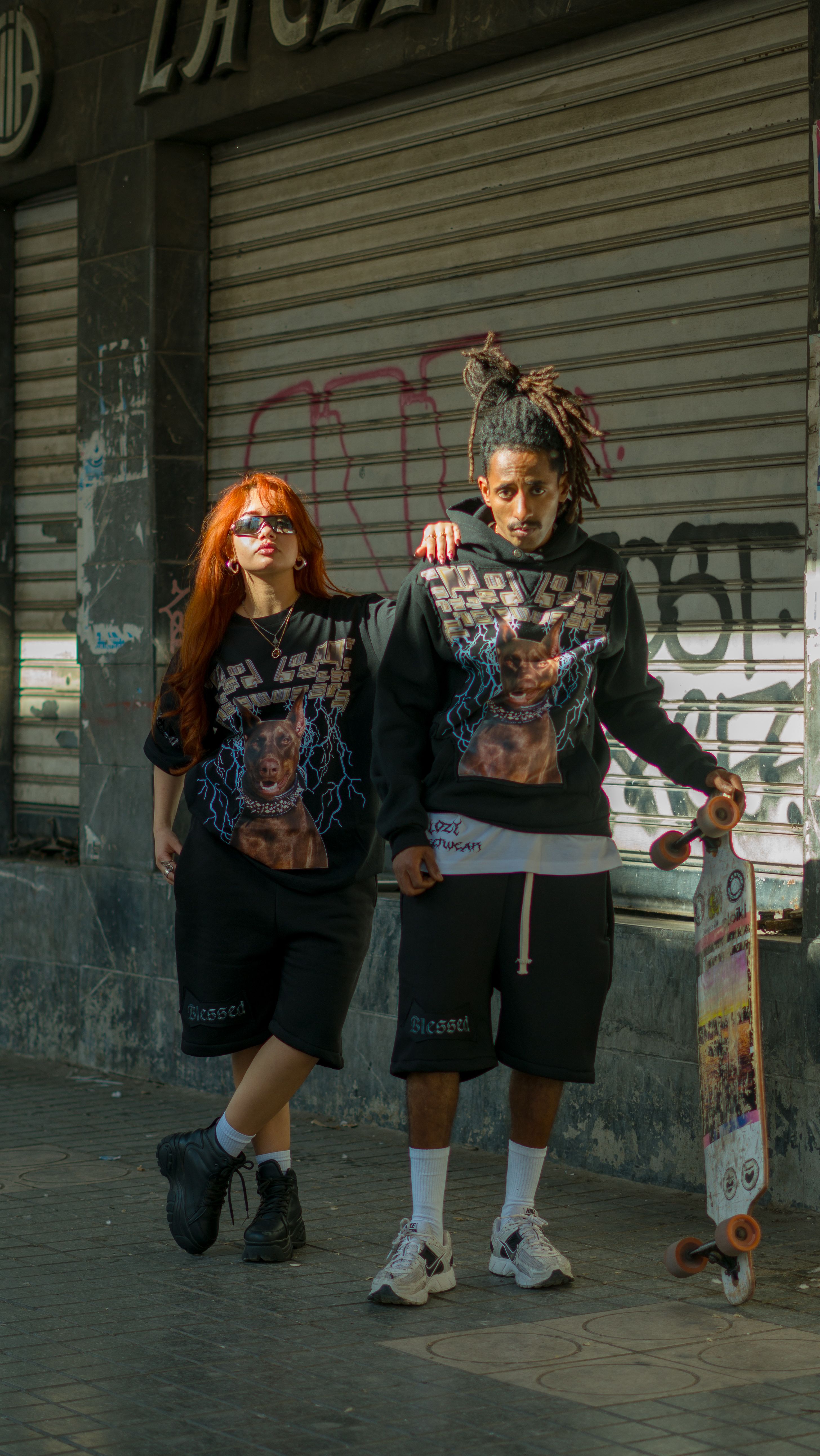 Young adults in streetwear posing with skateboard against graffiti backdrop in urban setting, Maroc.