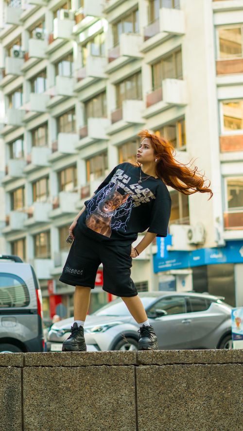 Free Young woman with vibrant red hair poses in urban street setting, showcasing modern fashion. Stock Photo
