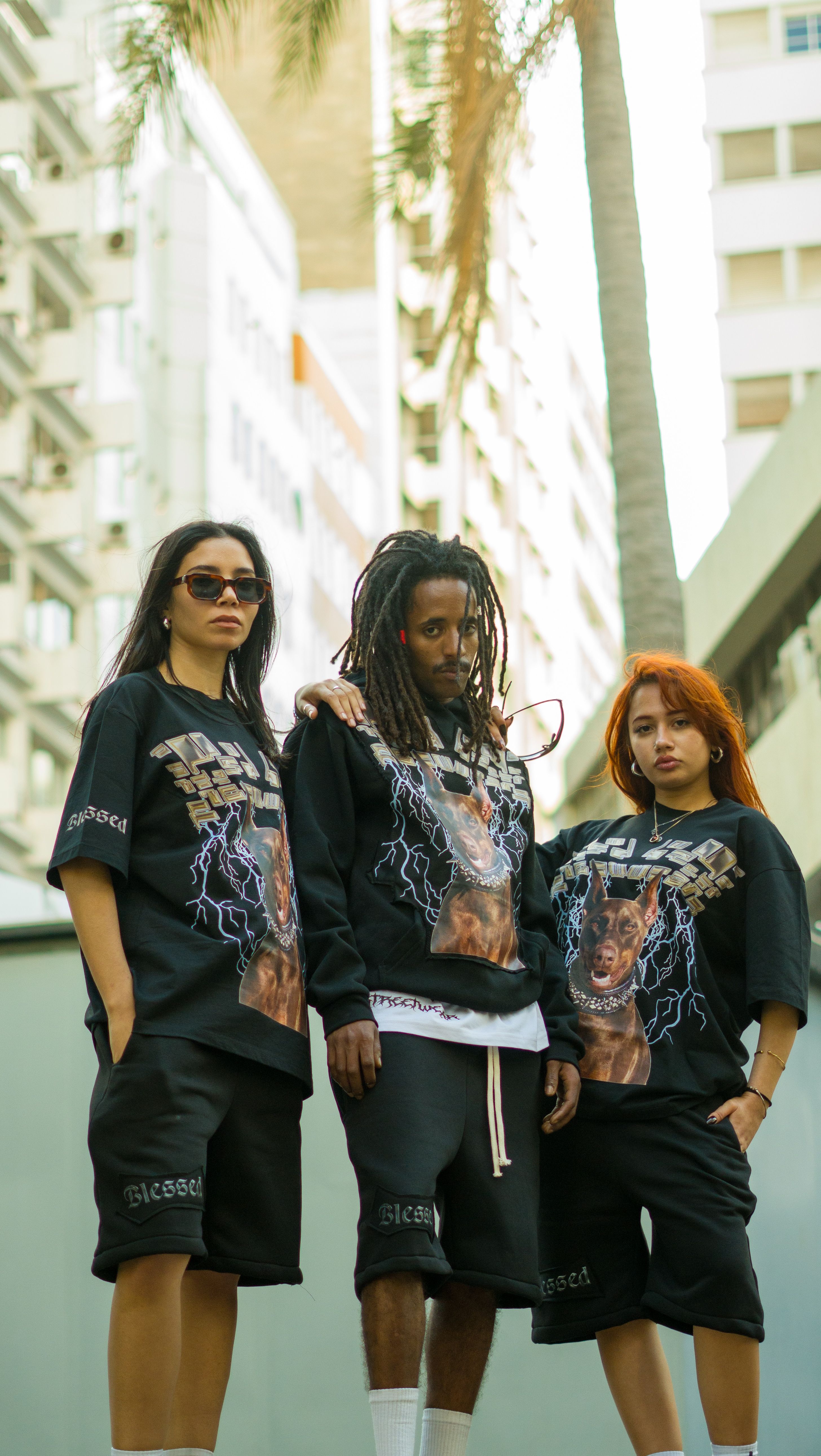 Three young adults showcase urban fashion against a Moroccan city backdrop, emphasizing modern streetwear.