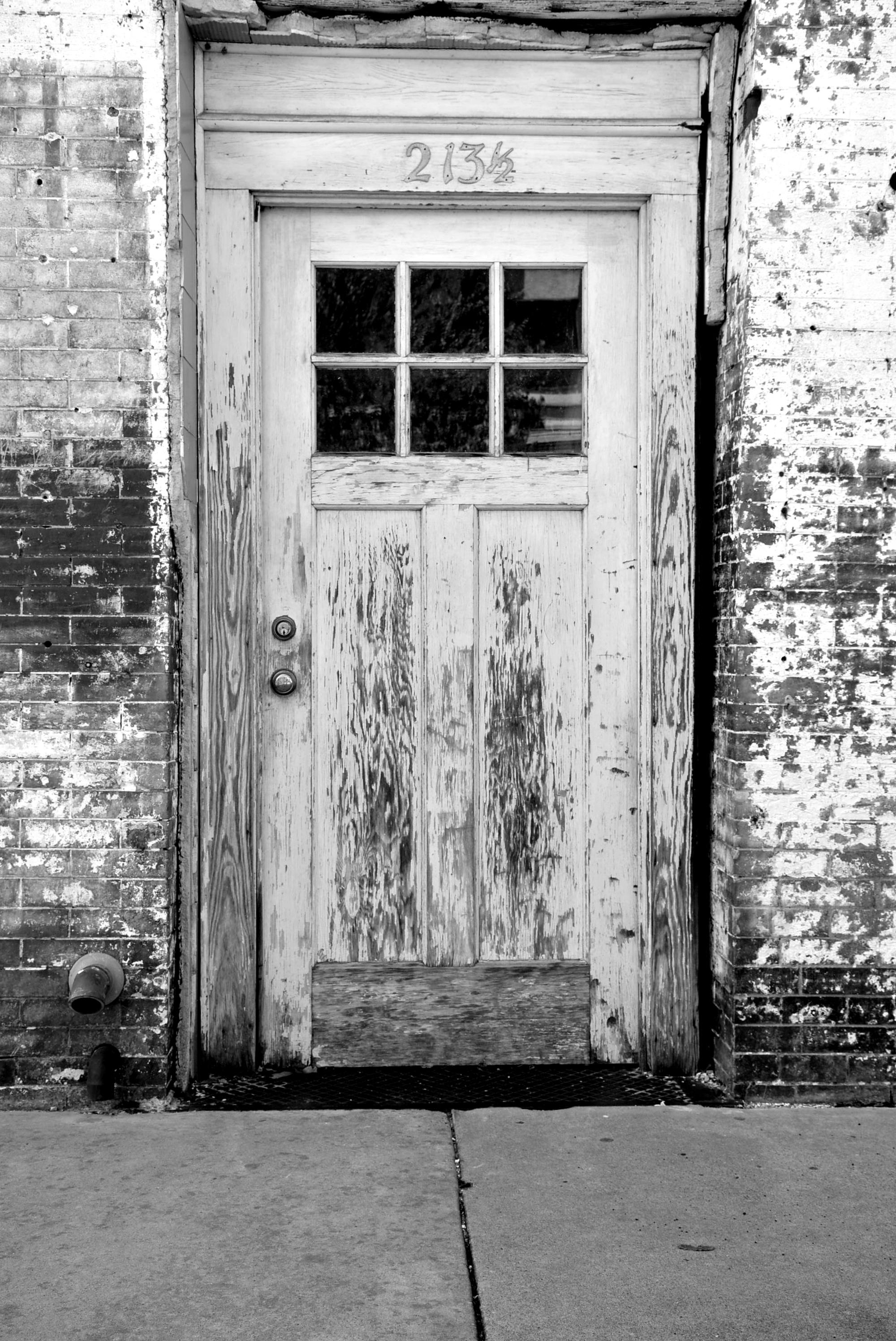 Black and white image of an old, weathered door in Tyler, Texas. Perfect for vintage enthusiasts.