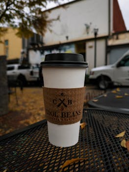 Coffee cup from Cool Beans roasters on a metal table, outdoors, fall setting.