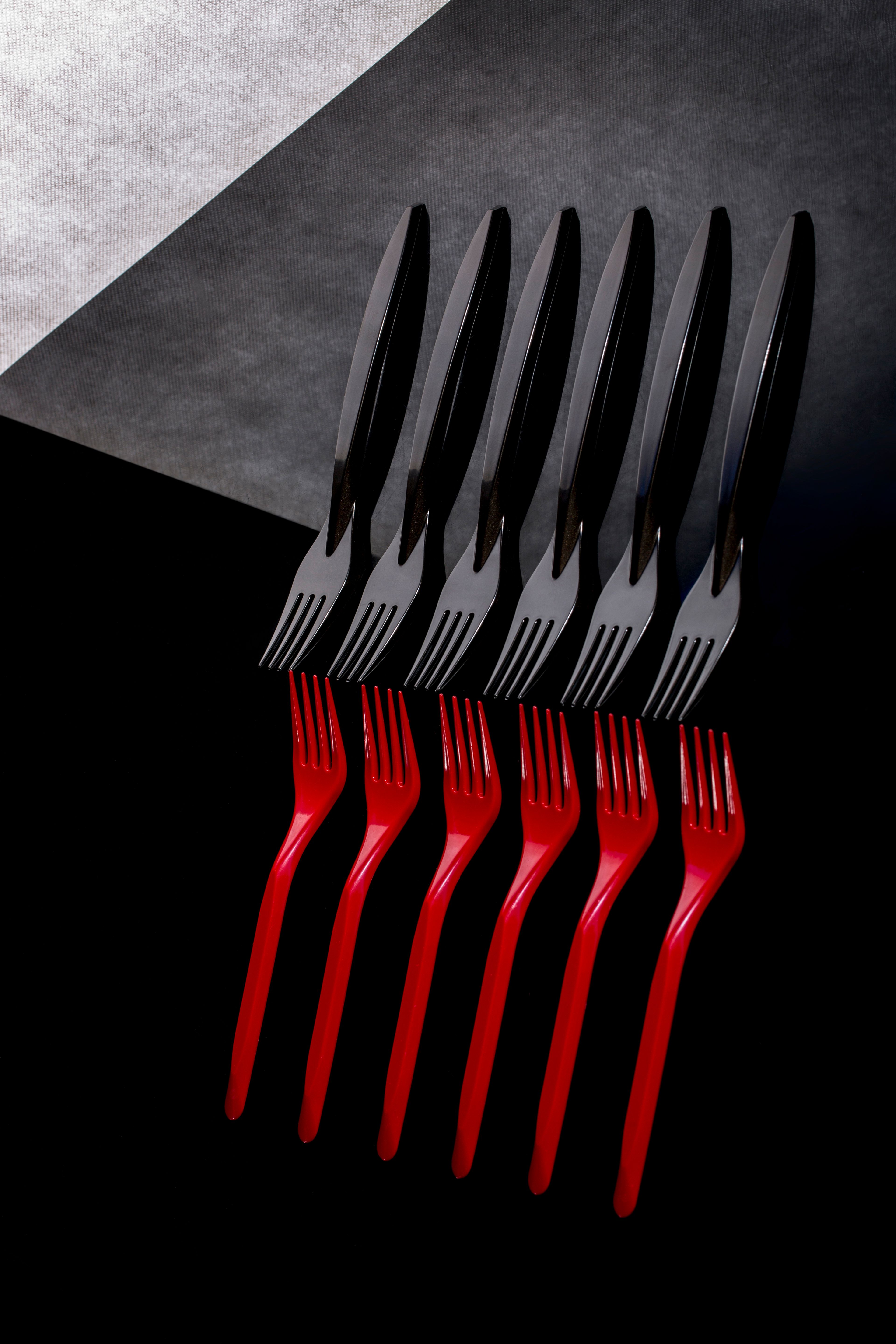 Modern abstract display of red and black forks and knives on dark background.