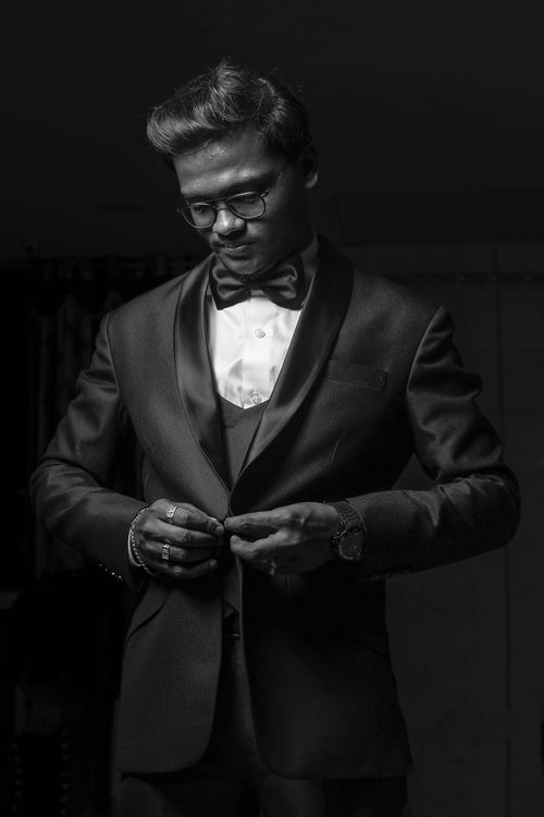 Free Black and white portrait of a man in a tuxedo, adjusting buttons. Elegant and sophisticated look. Stock Photo