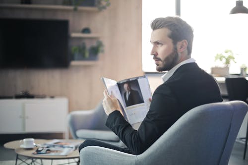 Free Man Sitting on Chair Holding a Magazine Stock Photo