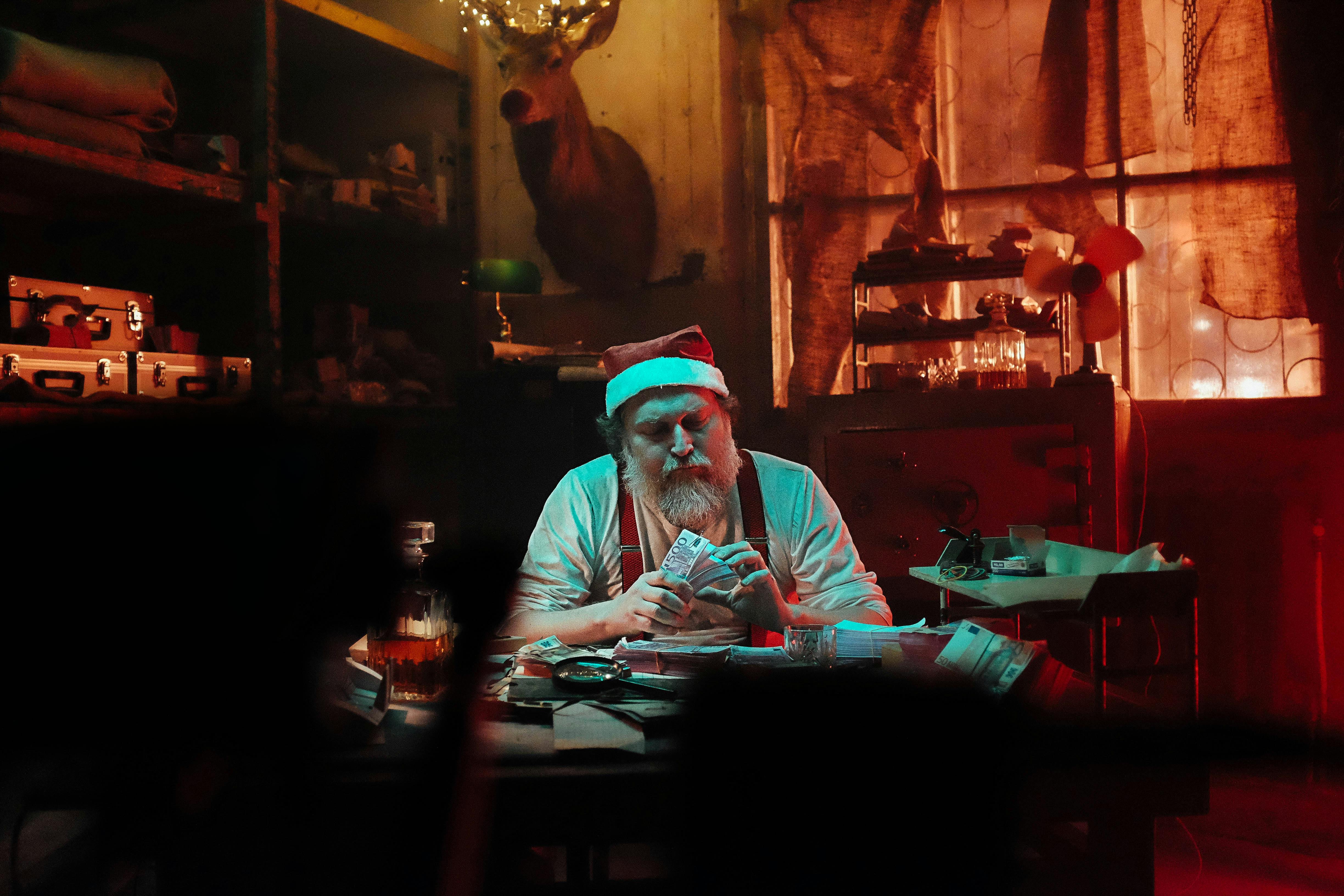 man in santa hat sitting on chair counting money