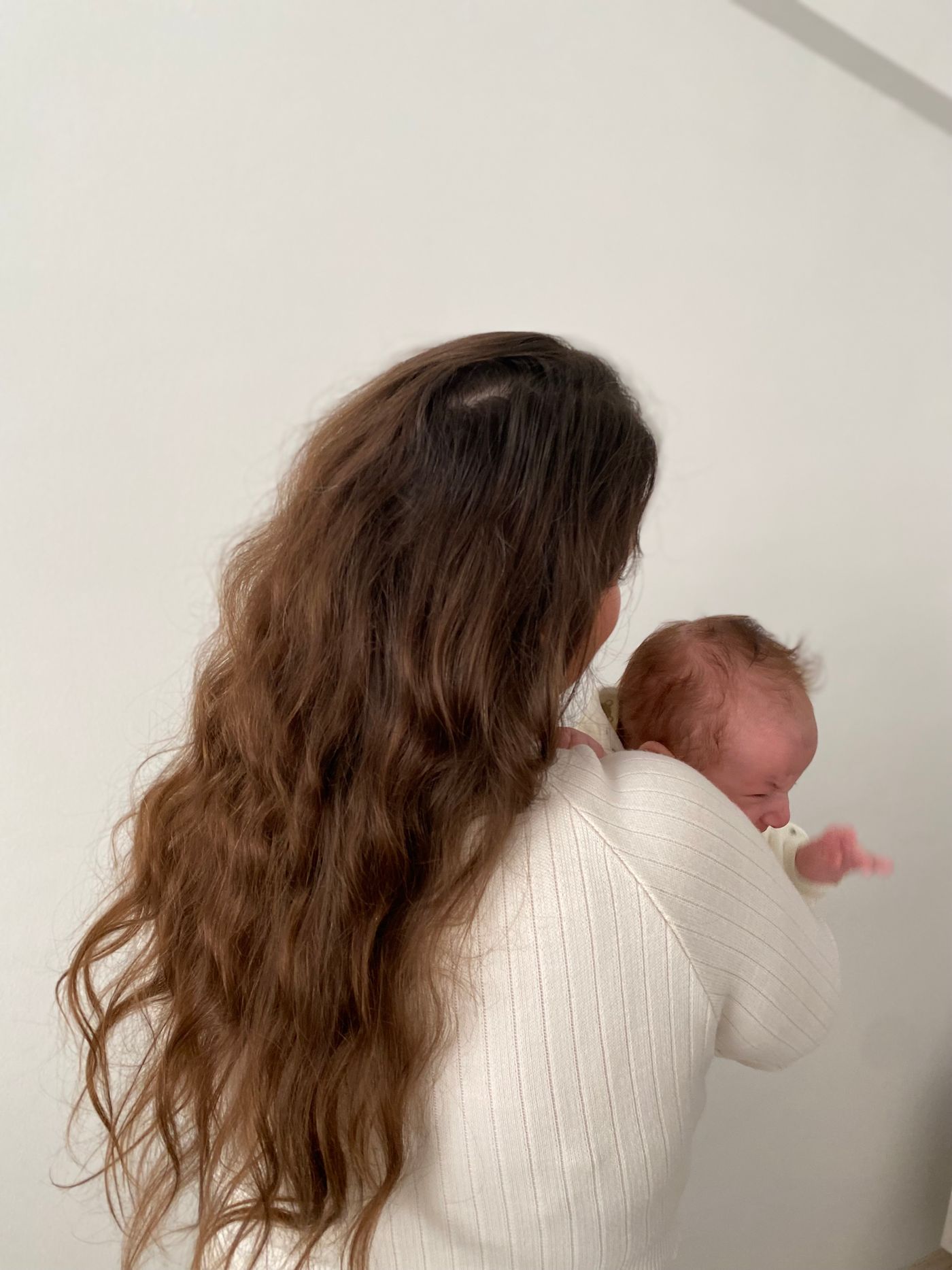 Jeune maman habillée portant son nouveau-né dans un intérieur chaleureux et lumineux