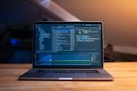 Modern Laptop on Wooden Desk with Code Displayed