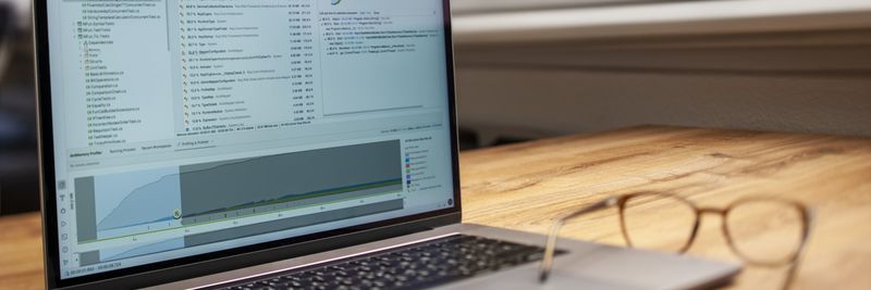 Modern laptop on a wooden desk displaying analytical software with eyeglasses nearby, indoor shot.