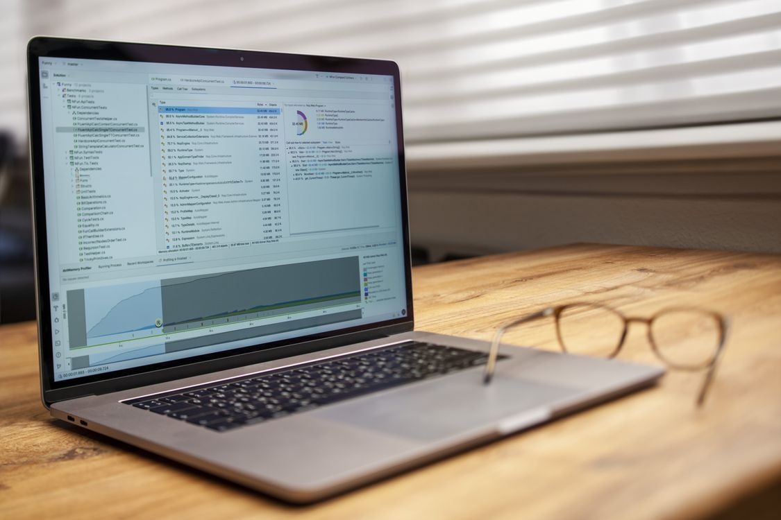 Laptop on a desk displaying analytical software next to reading glasses