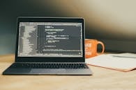 Laptop on Desk with Coding Screen and Coffee Mug