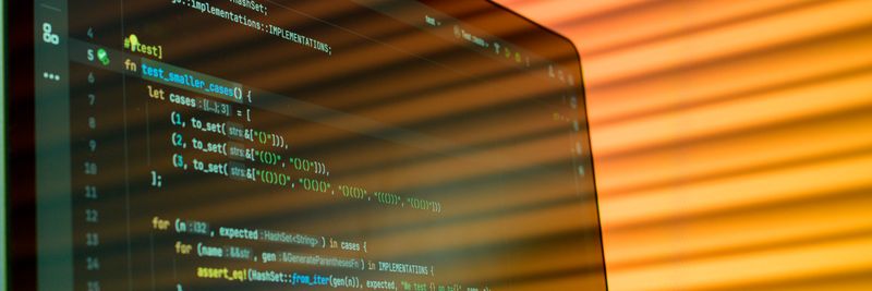 Blurry close-up of a computer screen displaying code with orange lighting.