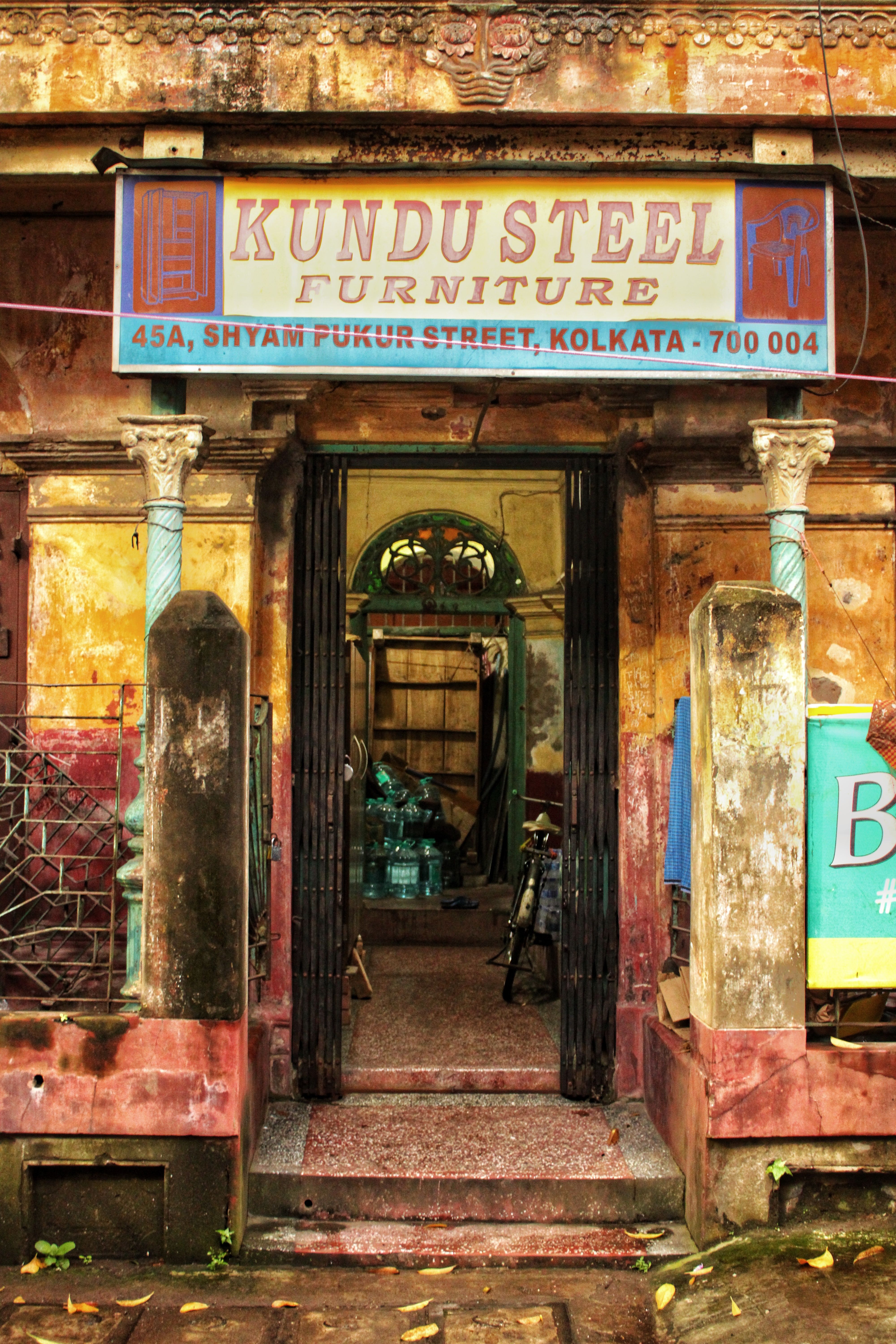 Vintage furniture shop entrance on Shyam Pukur Street, Kolkata showcasing rustic signage and architectural details.