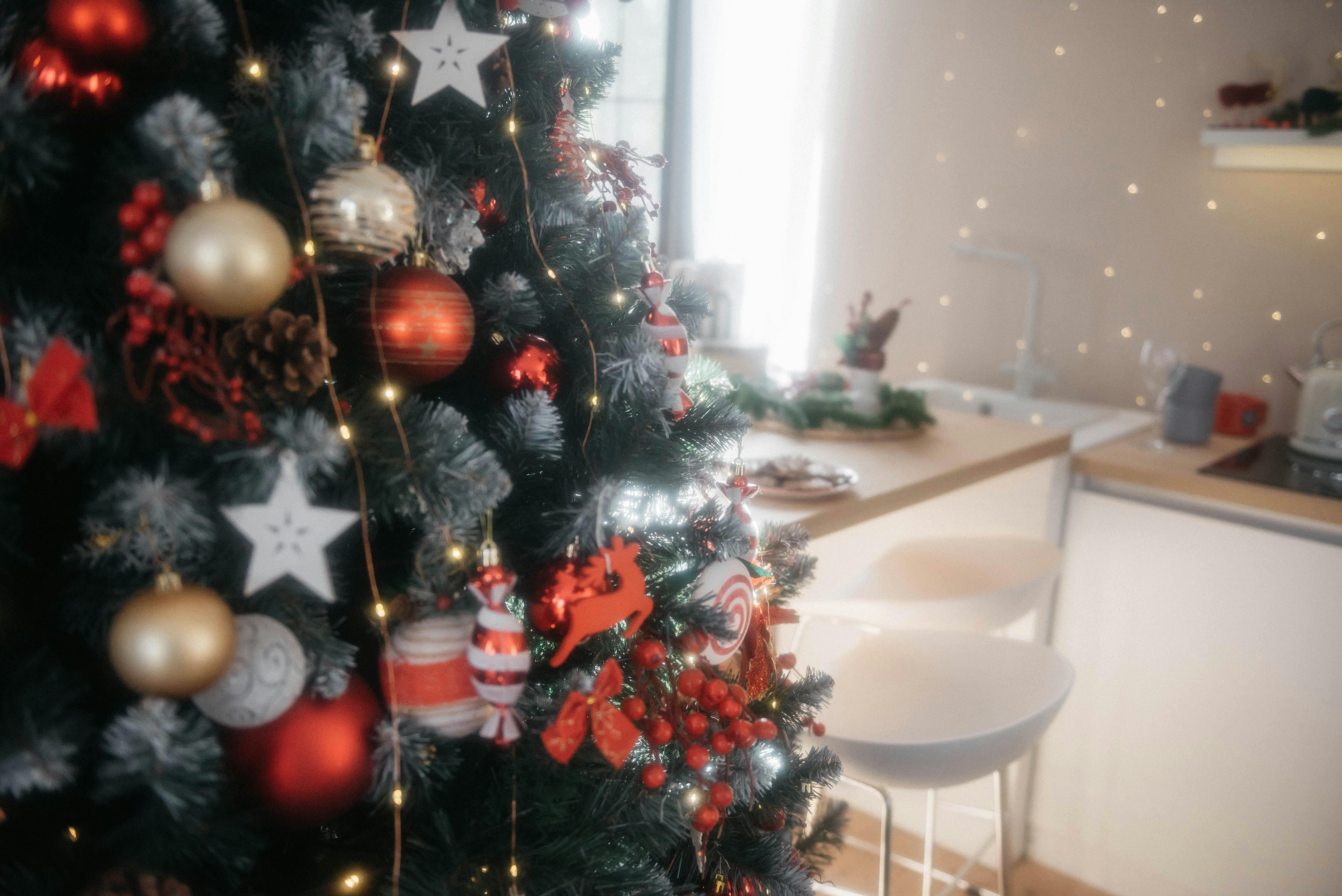A decorated Christmas tree with baubles and lights in a cozy kitchen.