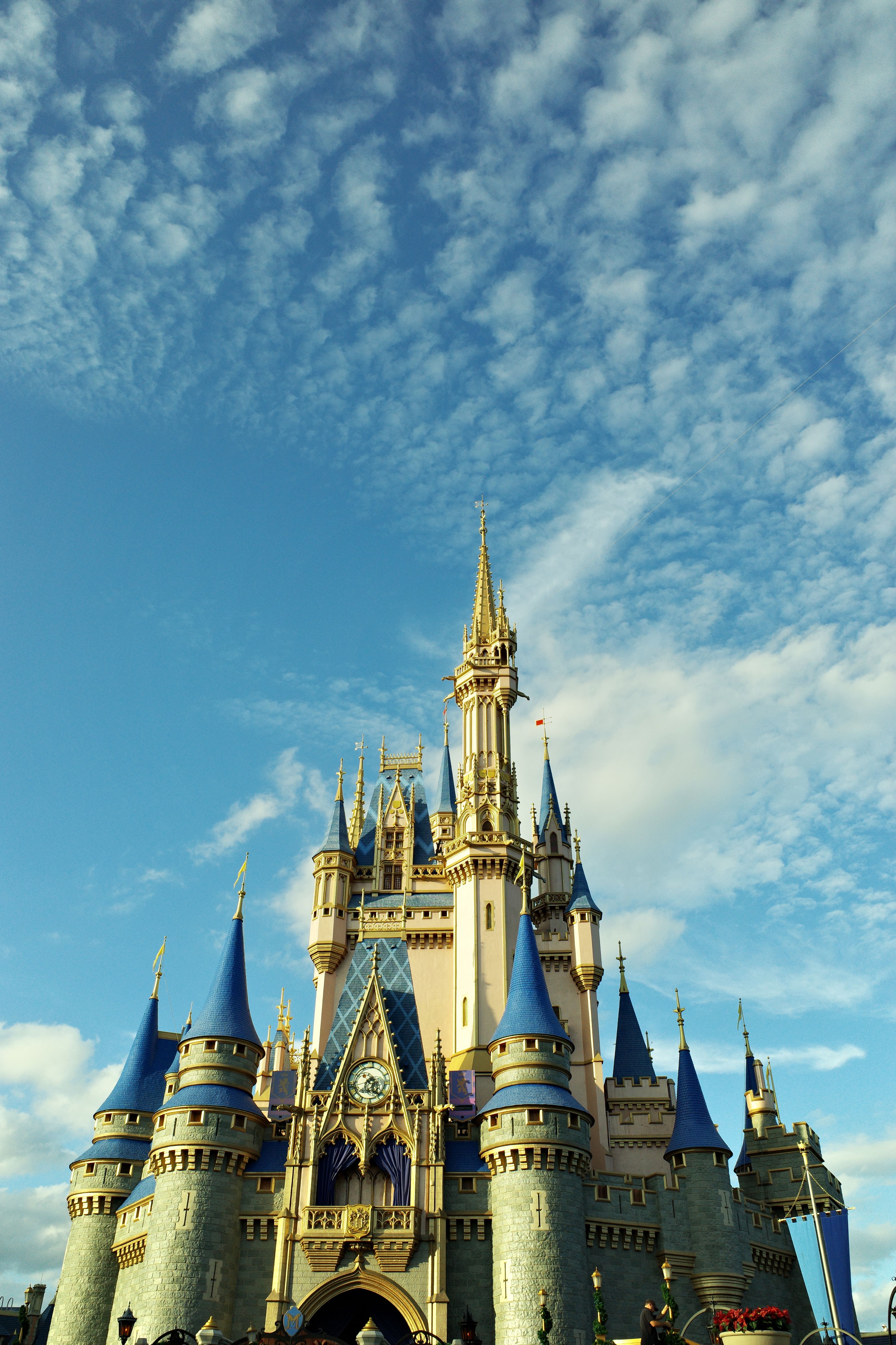 Vista de ângulo baixo do Castelo da Cinderela no Magic Kingdom, Orlando, Estados Unidos, elevando-se contra um céu azul brilhante com nuvens esparsas.