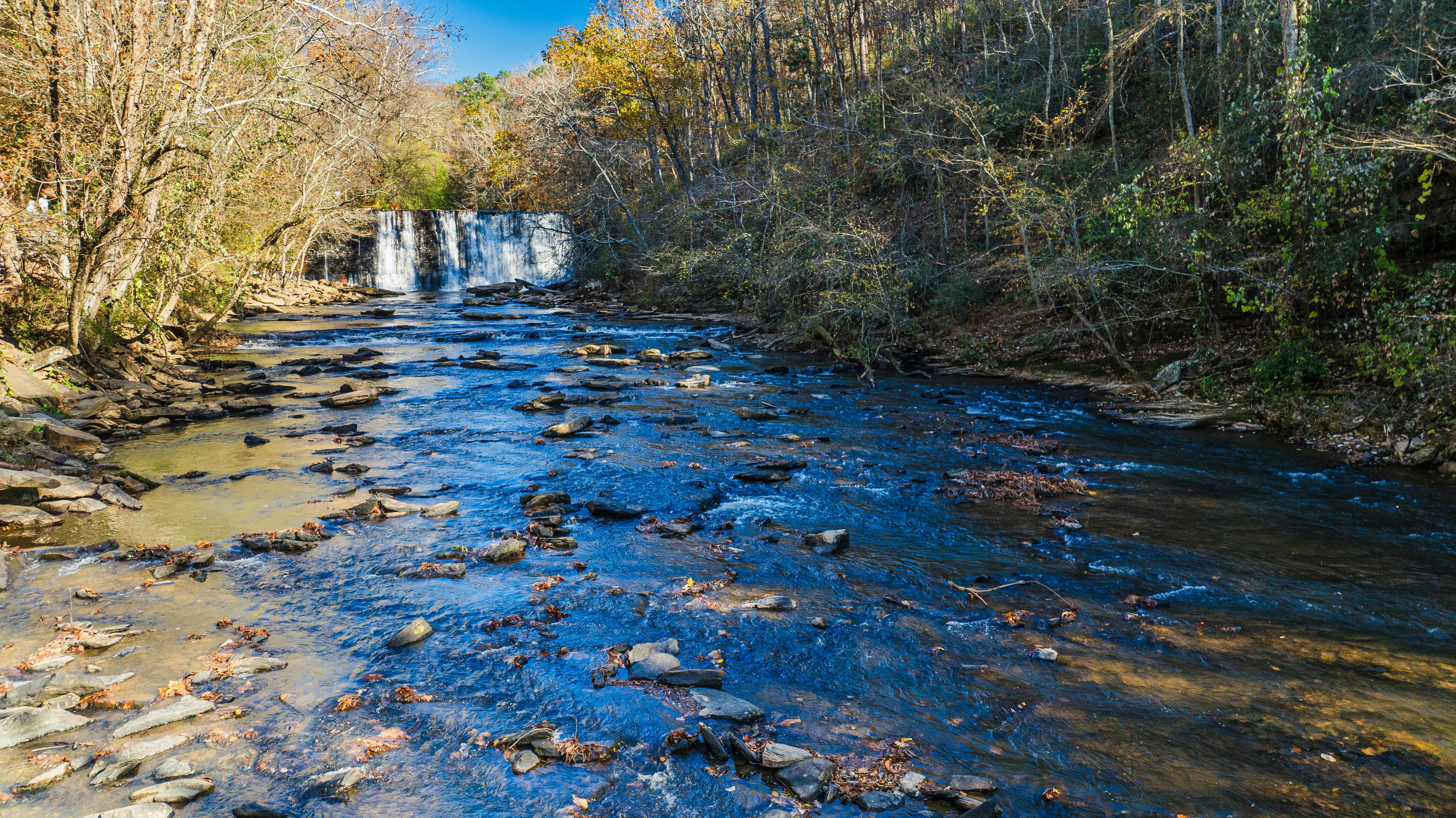 Scenic view of Roswell Mill Waterfall surrounded by autumn foliage in Georgia.