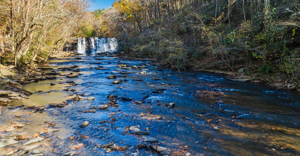 Scenic view of Roswell Mill Waterfall surrounded by autumn foliage in Georgia.