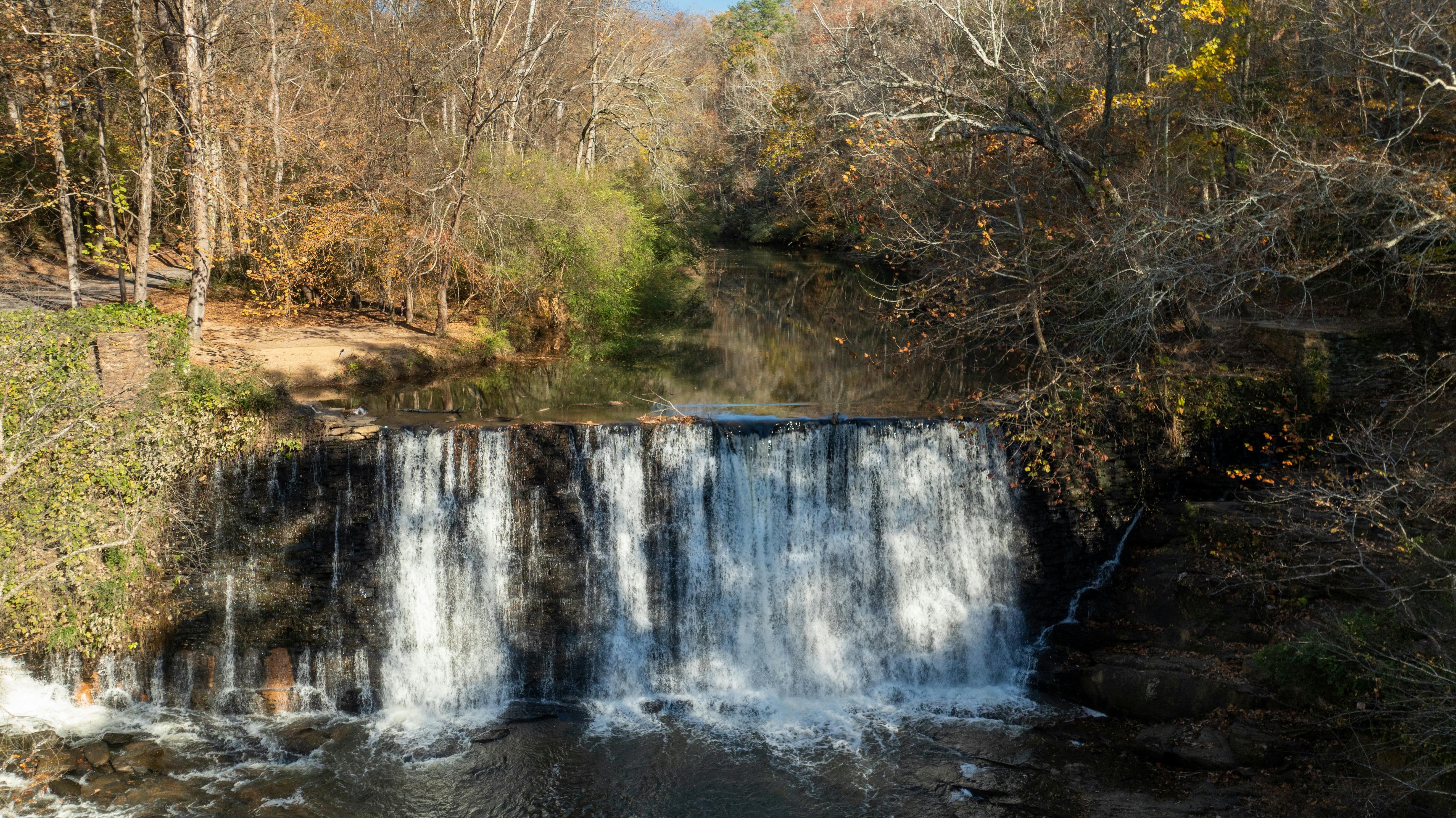 Serene view of Roswell Mill waterfall surrounded by autumn foliage.