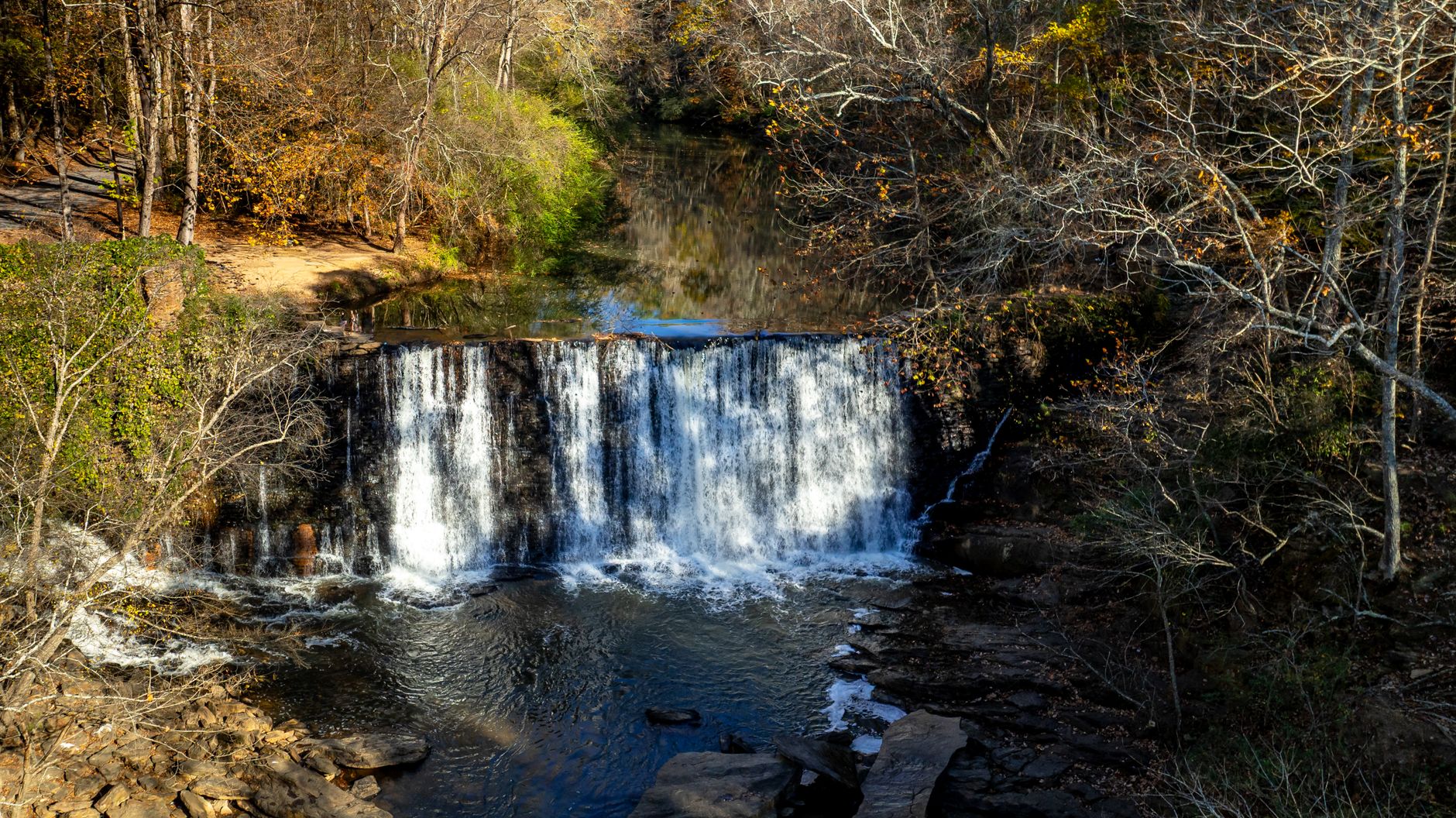 Beautiful waterfall at Roswell Mill, Georgia amidst autumn trees.