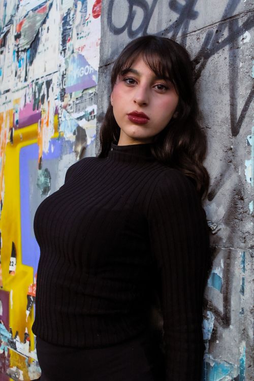 Free Stylish woman in black sweater poses against vibrant graffiti wall. Stock Photo