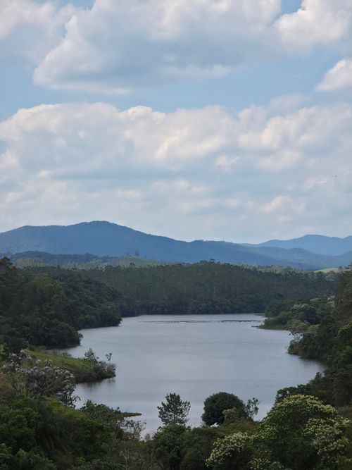 Free A serene river surrounded by lush green hills under a cloud-filled sky, perfect for nature lovers. Stock Photo