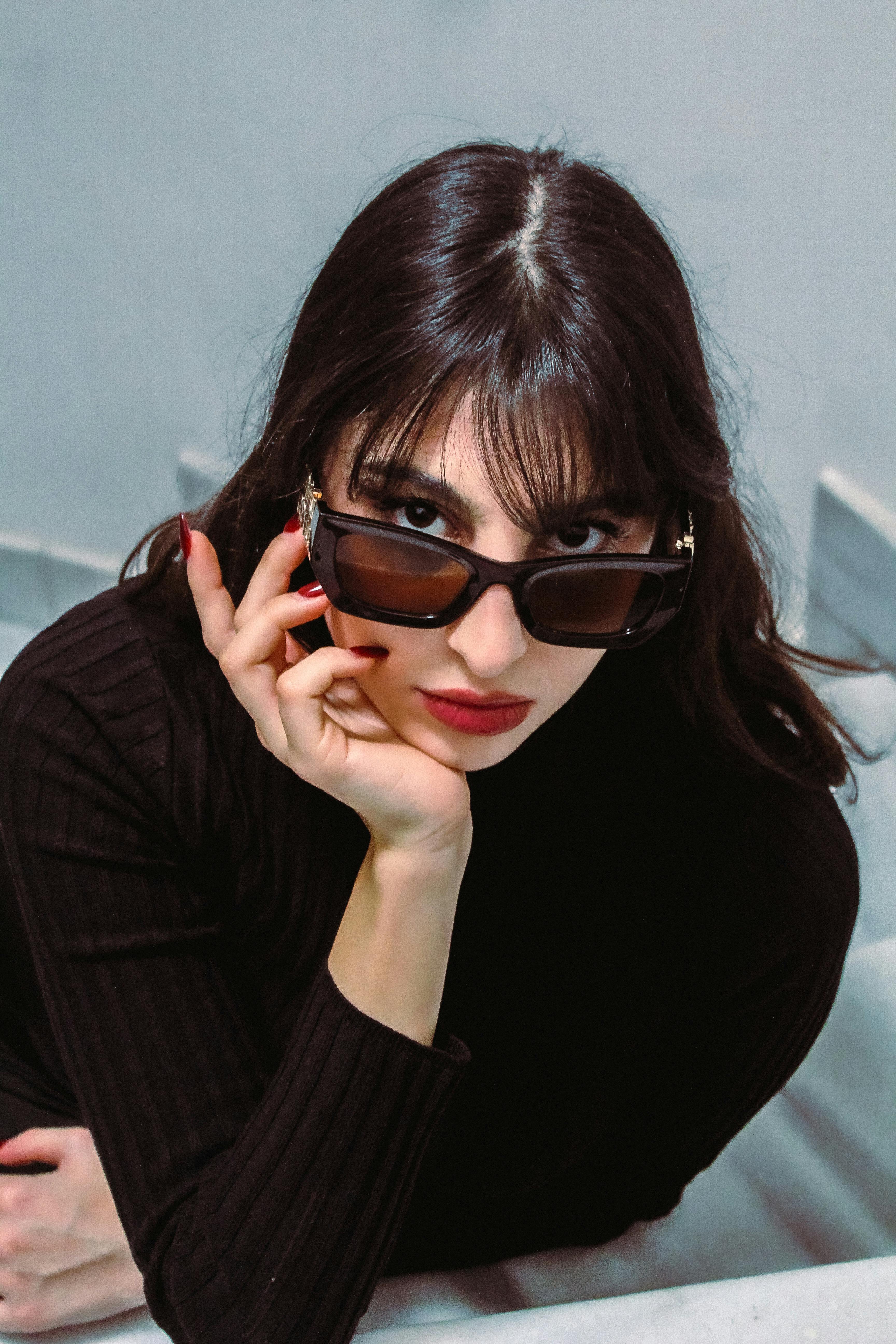 Miễn phí Người phụ nữ thanh lịch đeo kính râm tạo dáng tự tin trên cầu thang trong nhà. Ảnh lưu trữ