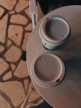 Two takeaway coffee cups on a café table, perfect for coffee enthusiasts.