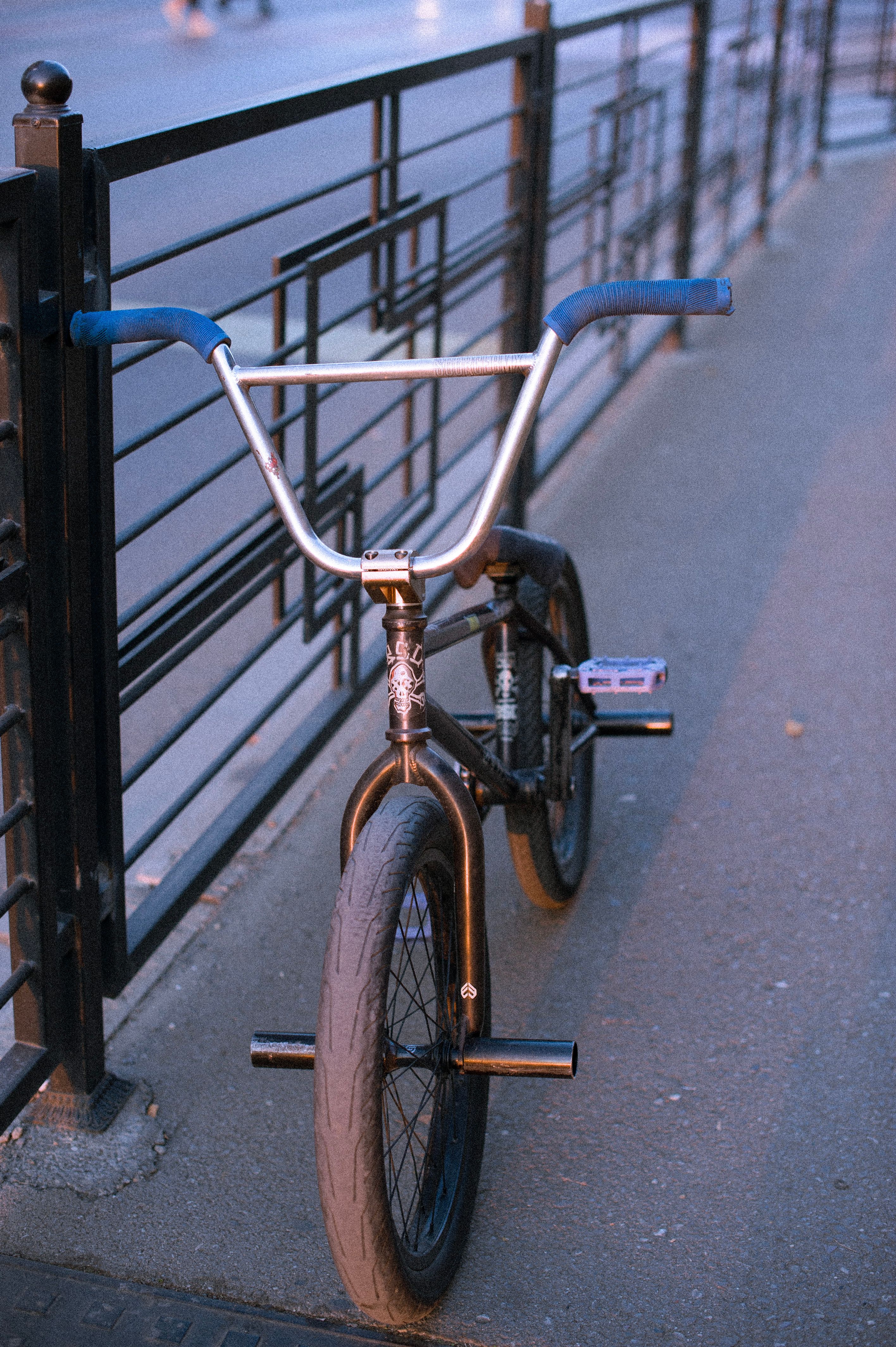 A BMX bike with blue handlebars parked on a city street during sunset in Tbilisi, Georgia.