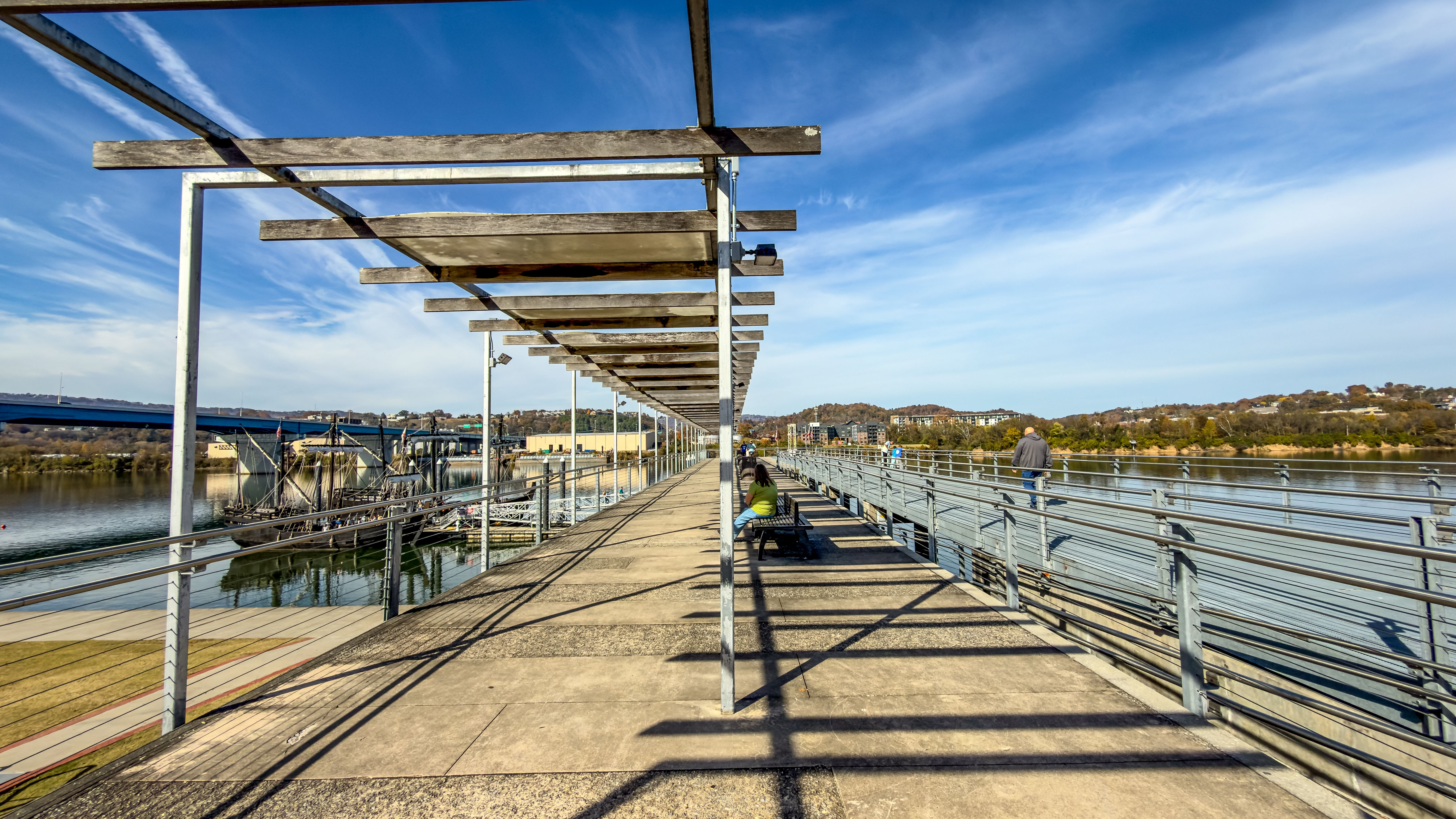 A sunny riverfront walkway beside a city river