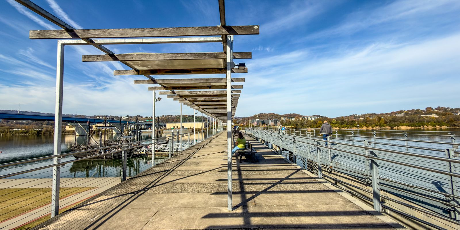 A sunny riverfront walkway beside a city river