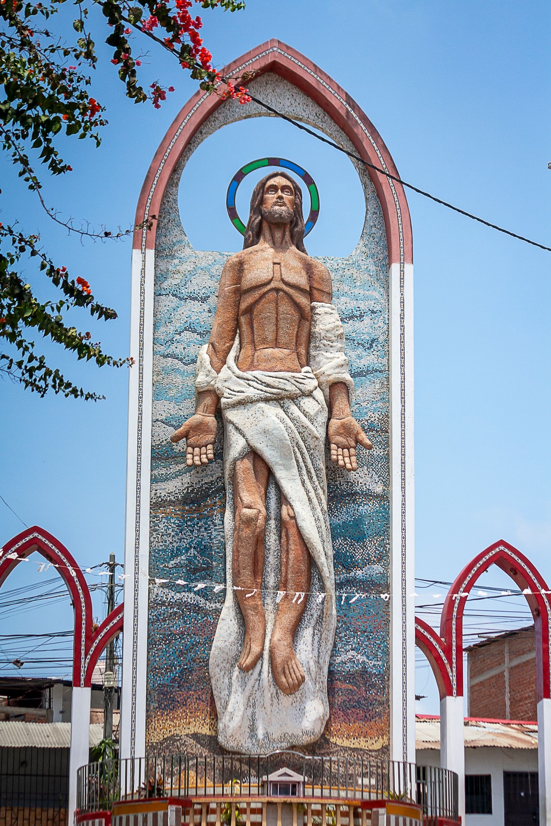 A towering sculpture of Jesus Christ in Tumbes, Peru with a bright and vibrant backdrop.