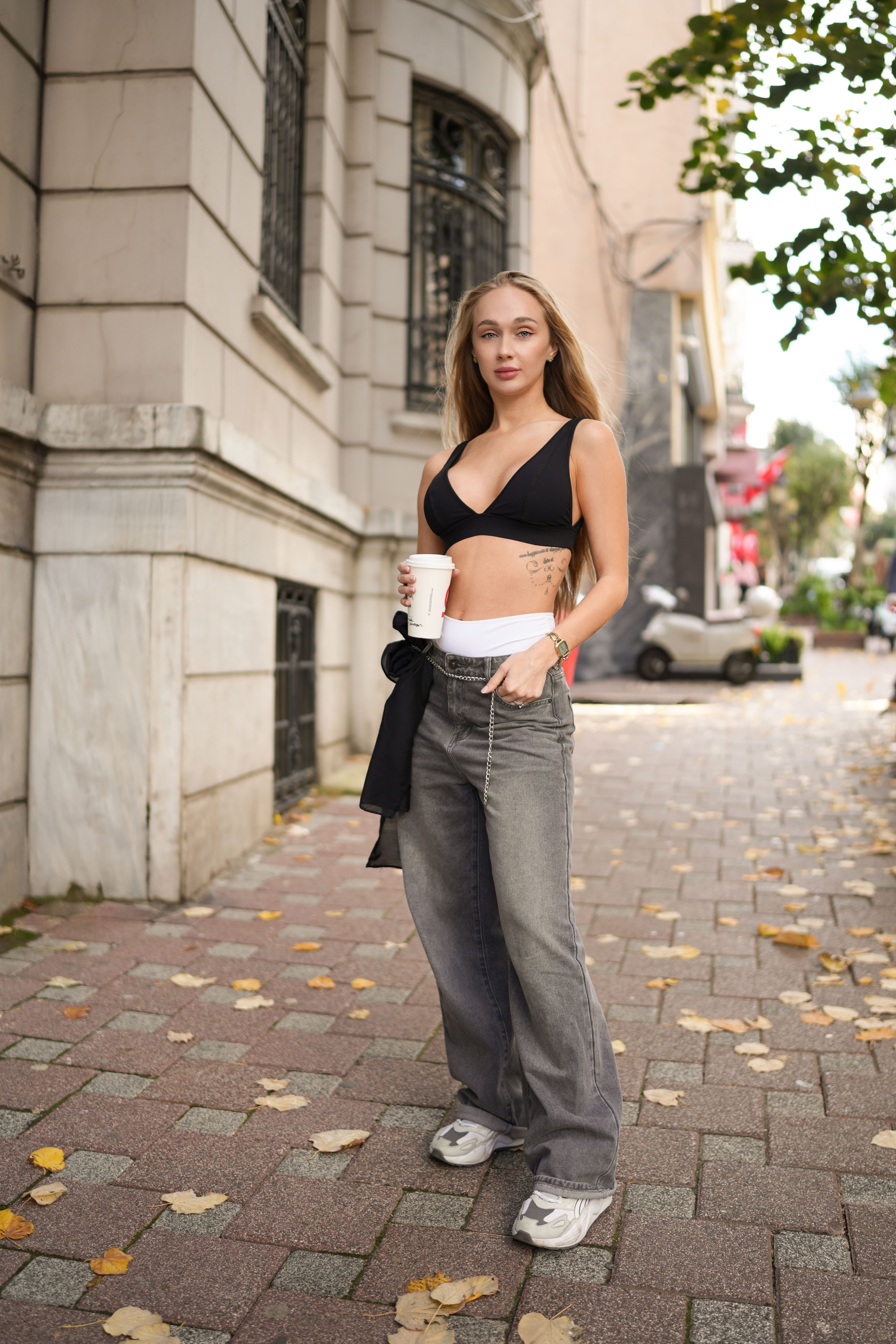 Stroll through an İstanbul street as a young woman enjoys her coffee on a pleasant day.