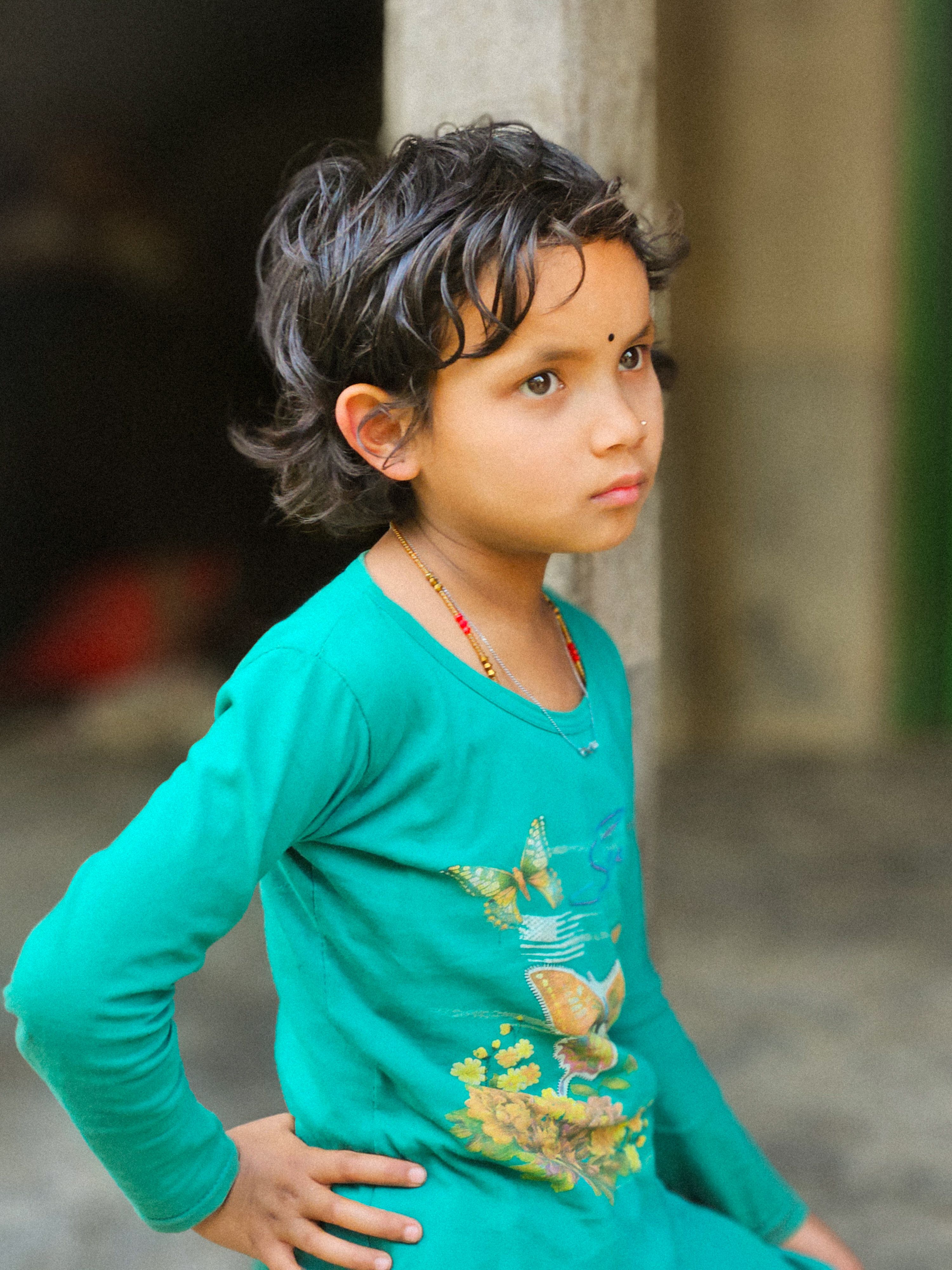 Contemplative Child in Green Shirt Indoors · Free Stock Photo