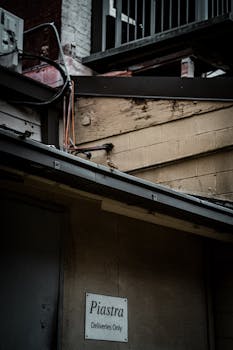 Moody urban alleyway with a 'Deliveries Only' sign and rustic buildings.
