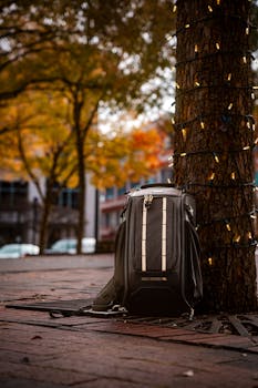 A modern backpack set against an autumnal urban backdrop with fairy lights.