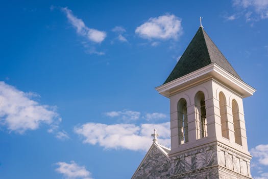 A classic church tower set against a clear blue sky with soft clouds.