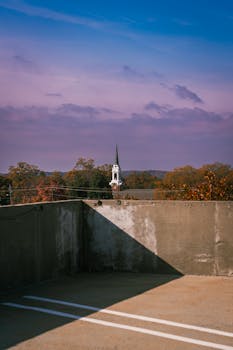 A church steeple rises above autumn trees under a vibrant sky.